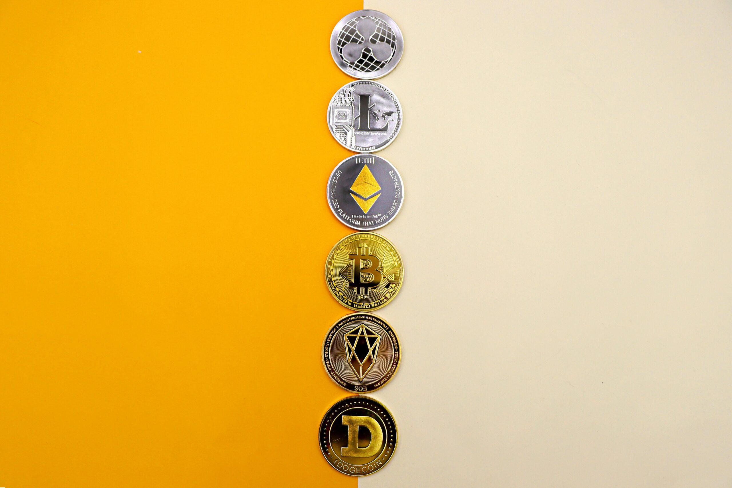 A row of cryptocurrency coins including Bitcoin, Ethereum, and Dogecoin on a vibrant yellow surface.